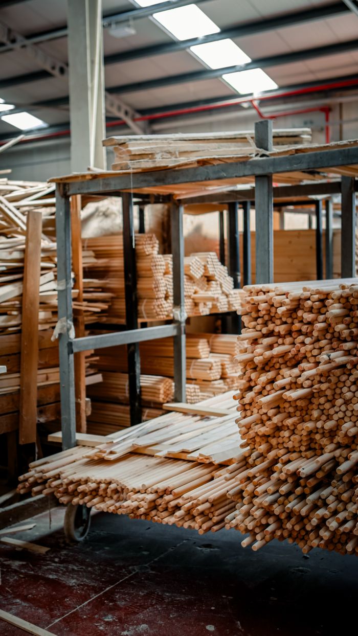 Vertically piled wooden materials neatly arranged in an indoor warehouse setting.